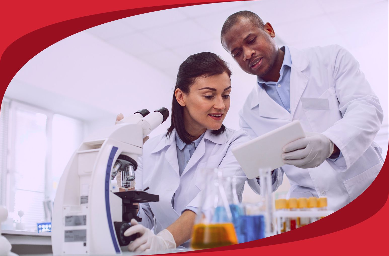 Two professionals stand at a microscope