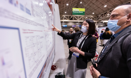An speaker presents her abstract poster to an attendee