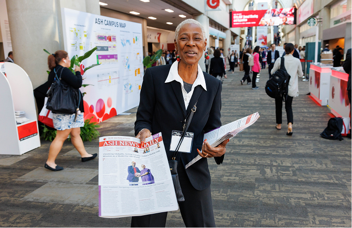 A woman showcasing the ASH News Daily during the ASH annual meeting
