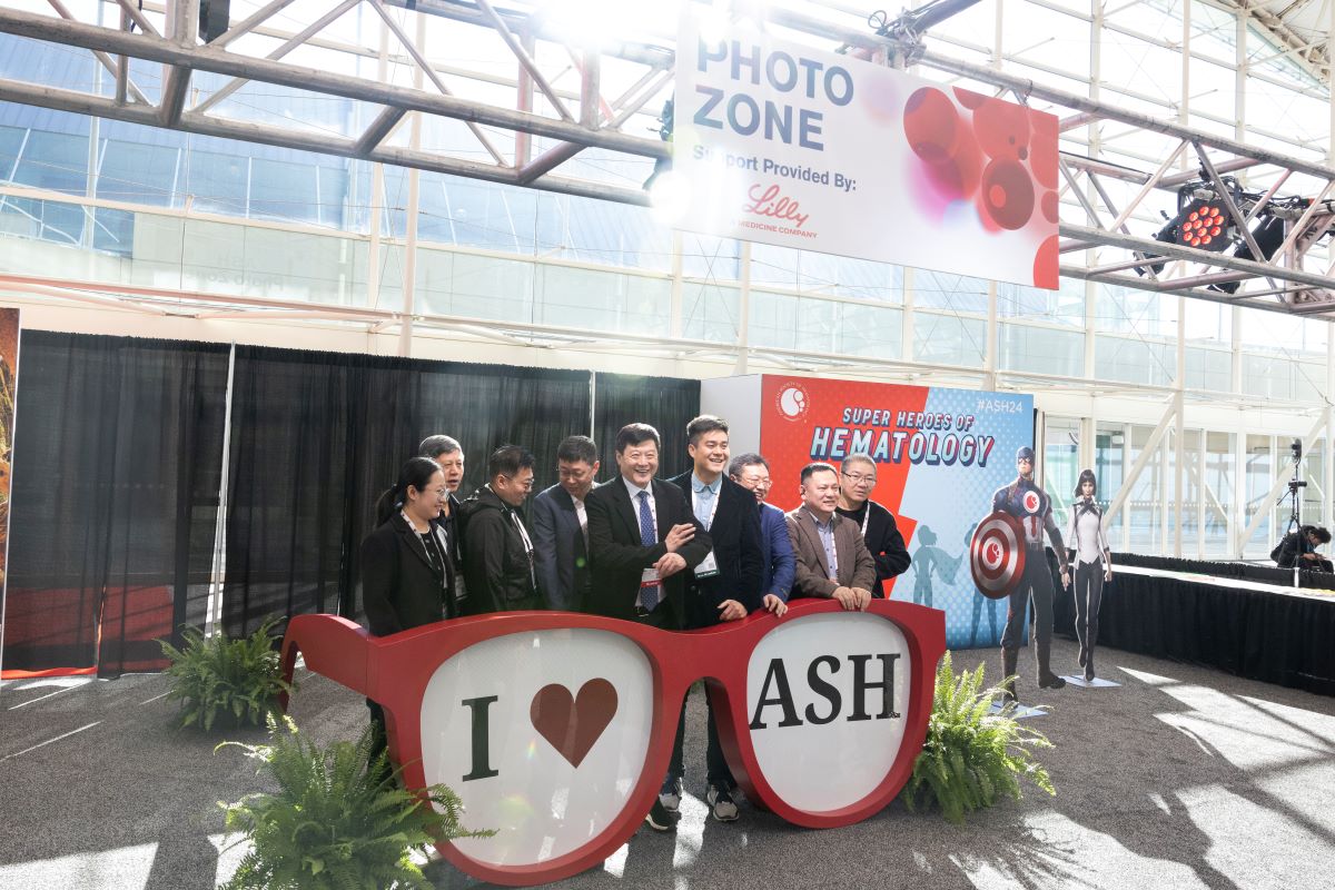 Attendees gather for a photo behind a giant I Love ASH Sunglass display.