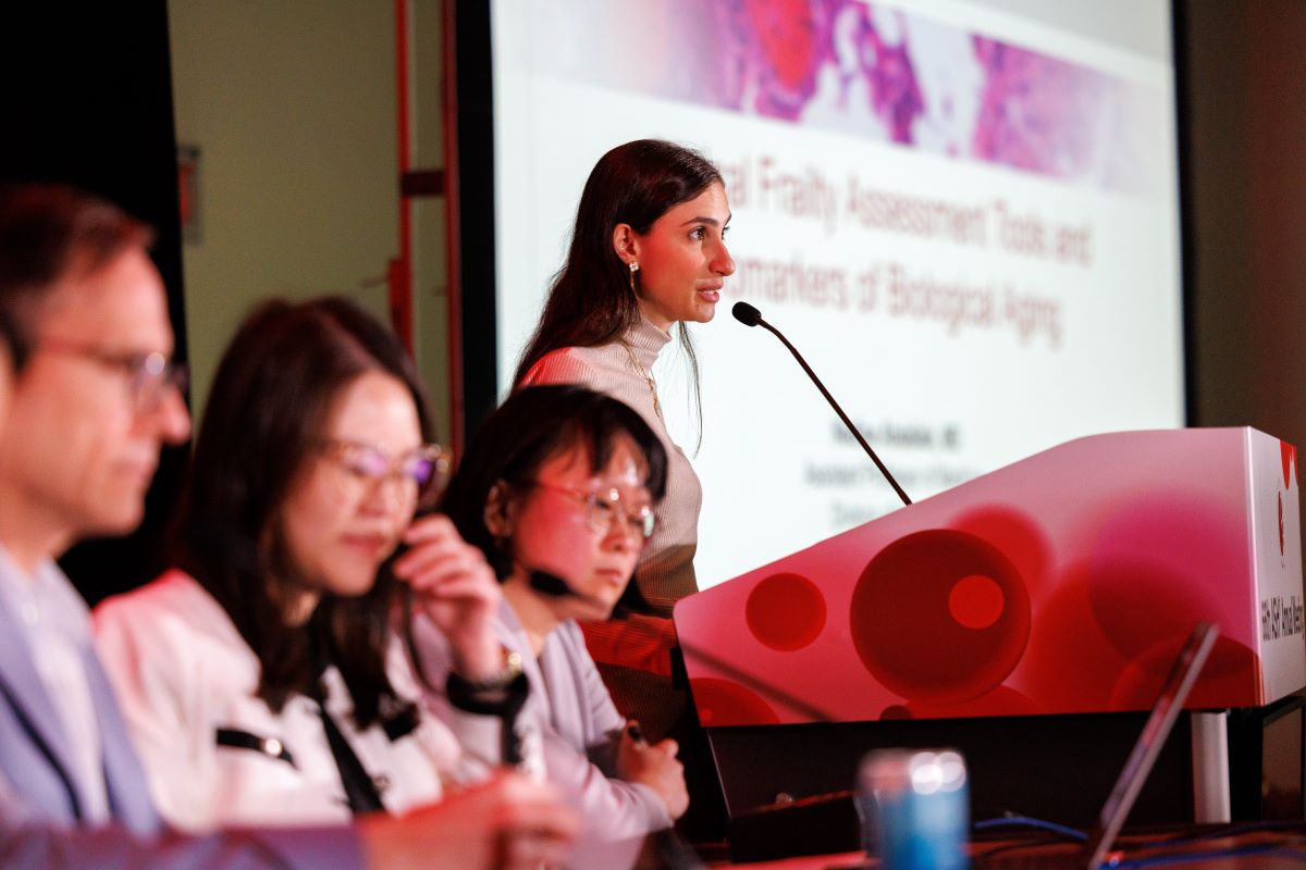 A woman stands at a podium giving a presentation.