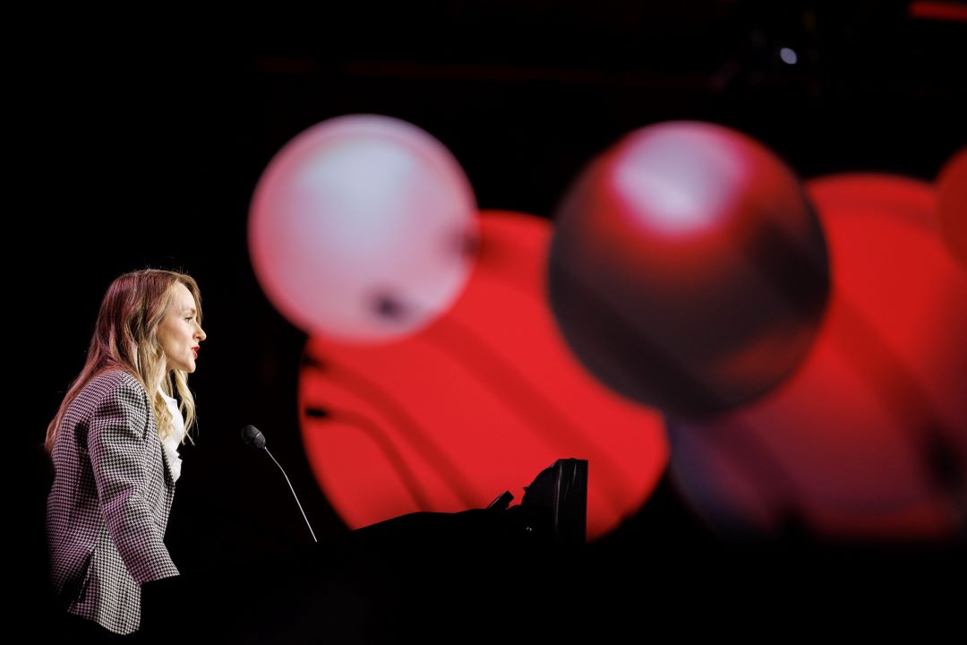 A speaker presents a plenary lecture in the main meeting hall.