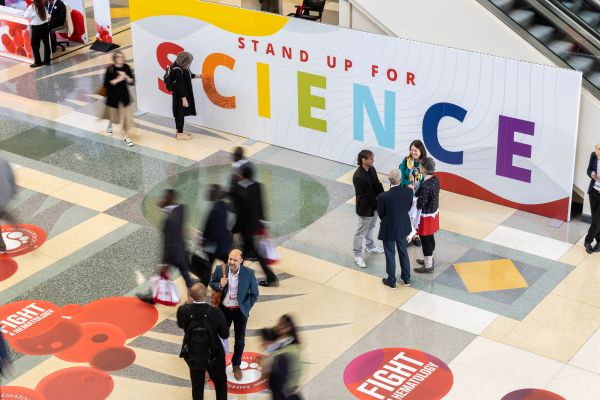 People walk by a stand for science sign at the annual meeting