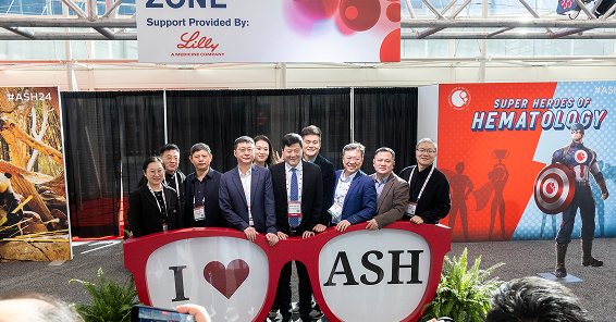 A group of posing for a photo during the Annual meeting with a big glasses with inscription I love ASH